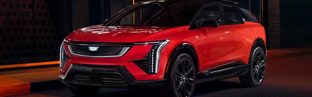 Red 2026 Cadillac OPTIQ driving down road at night