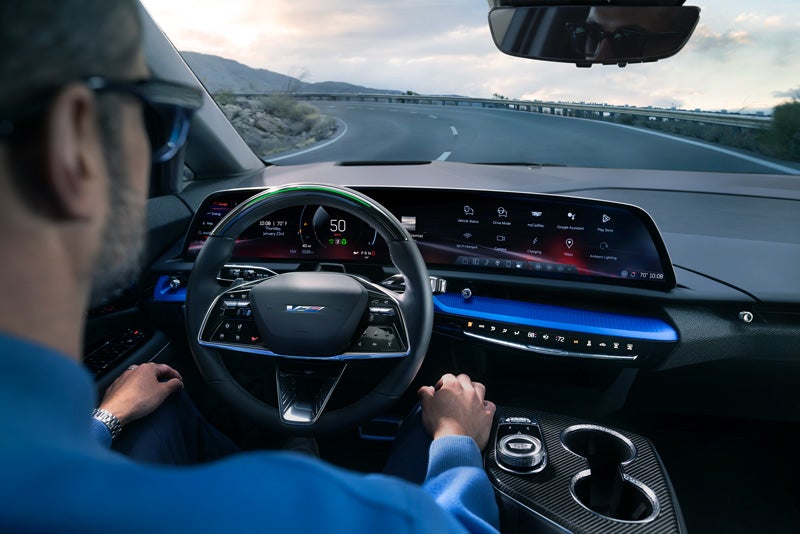 Front View of the 2026 OPTIQ-V Driving Through the Dusk Utilizing its Headlights | Spence Cadillac in Thomasville GA