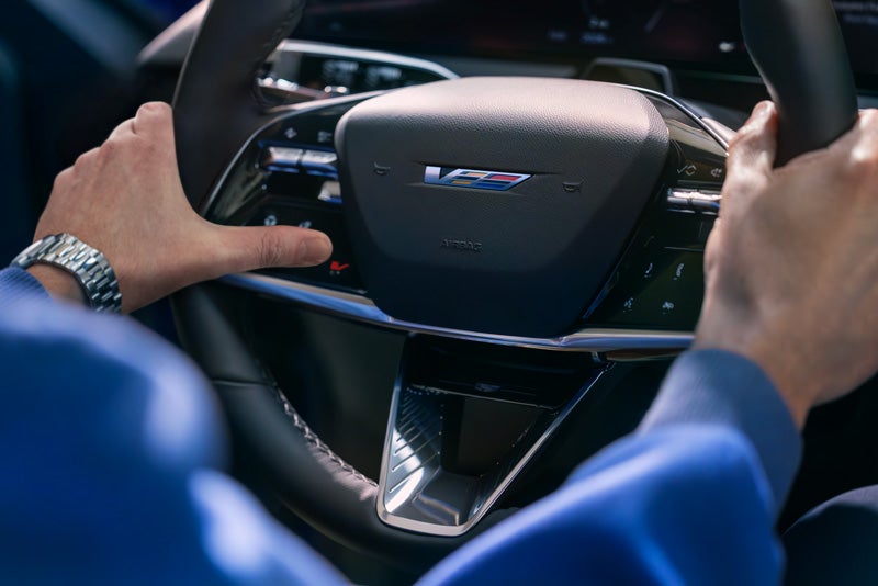 Close-up of a Man About to Press the V-Button on the 2026 OPTIQ-V Steering Wheel | Spence Cadillac in Thomasville GA