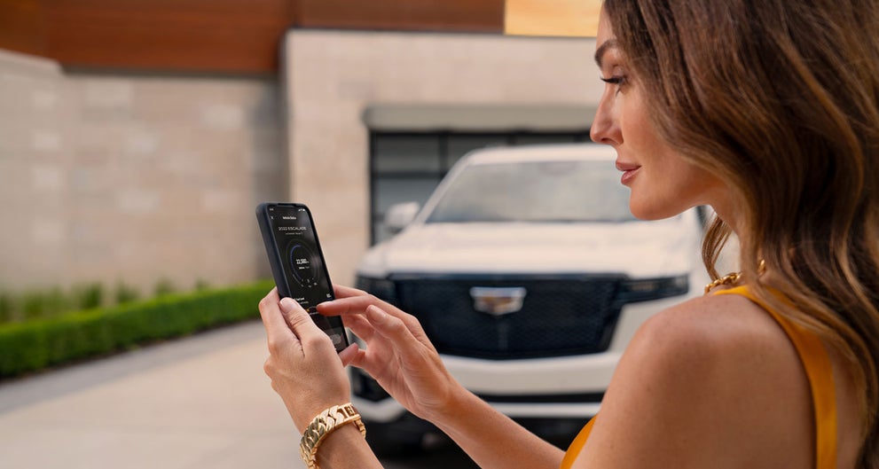 lady checking her mobile with a Cadillac vehicle background | Spence Cadillac in Thomasville GA